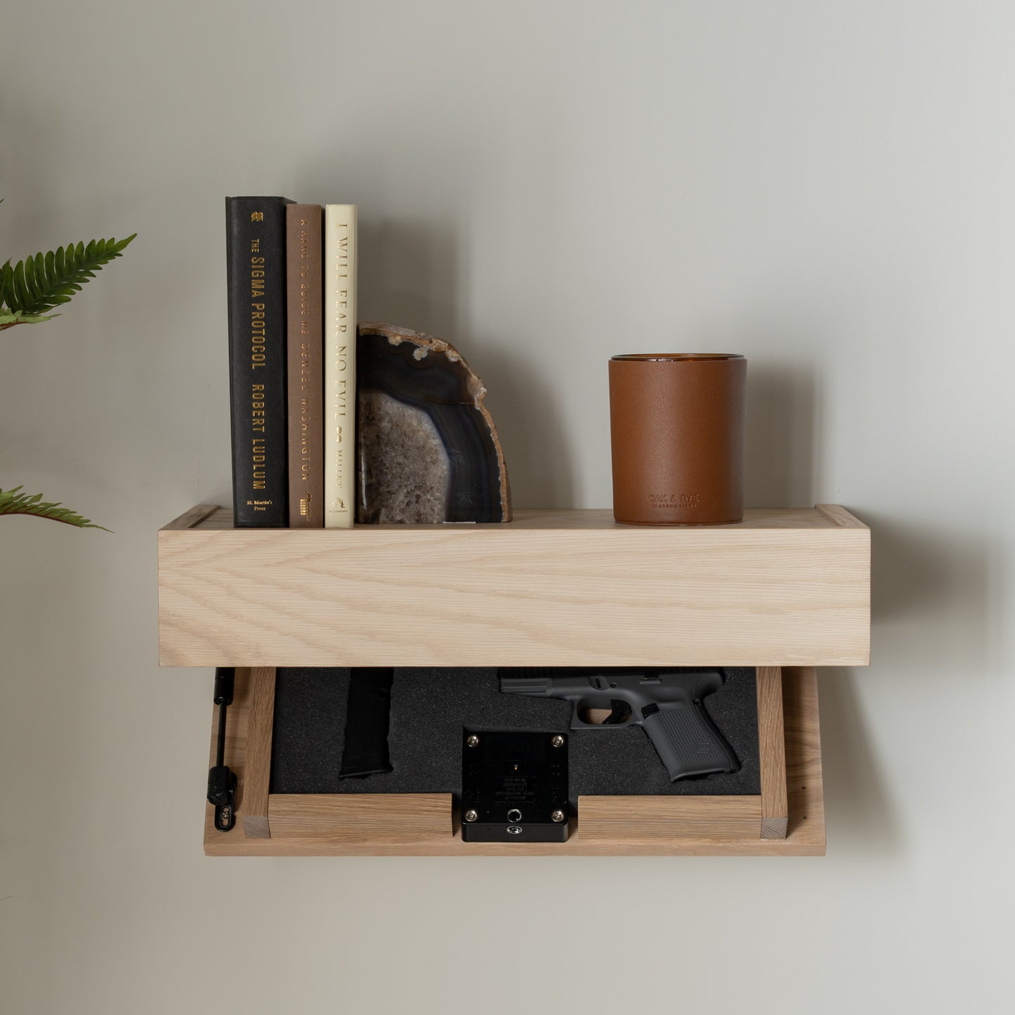 Murphy Door® concealed shelf with handgun storage, featuring light wood finish, books, agate bookend, and brown candle holder.