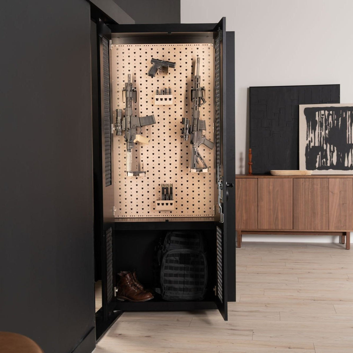 Murphy Door® hidden gun cabinet with pegboard interior displaying firearms, black exterior, storage below for boots and tactical gear.