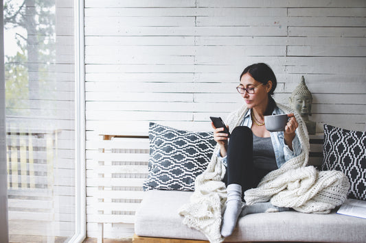 woman curled up with a cozy throw reading about how to store blankets