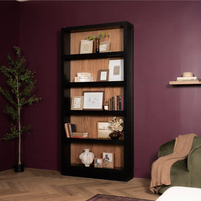 Murphy Door® hidden bookcase door. Tall black frame with wood-toned interior shelves, styled with decor in a red room.