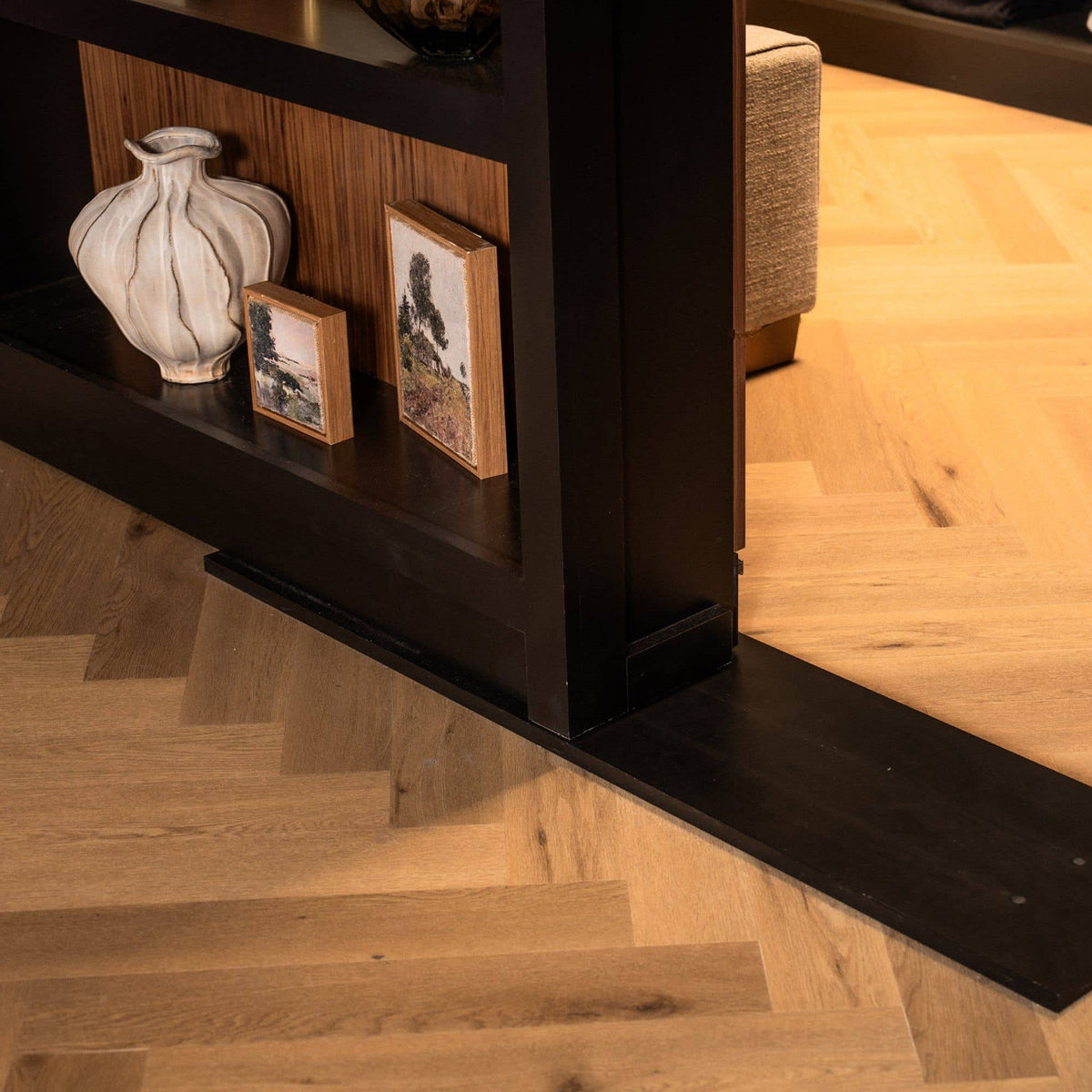 Murphy Door® dark wood hidden bookcase with decorative items on shelves, blending into light herringbone wood floor.