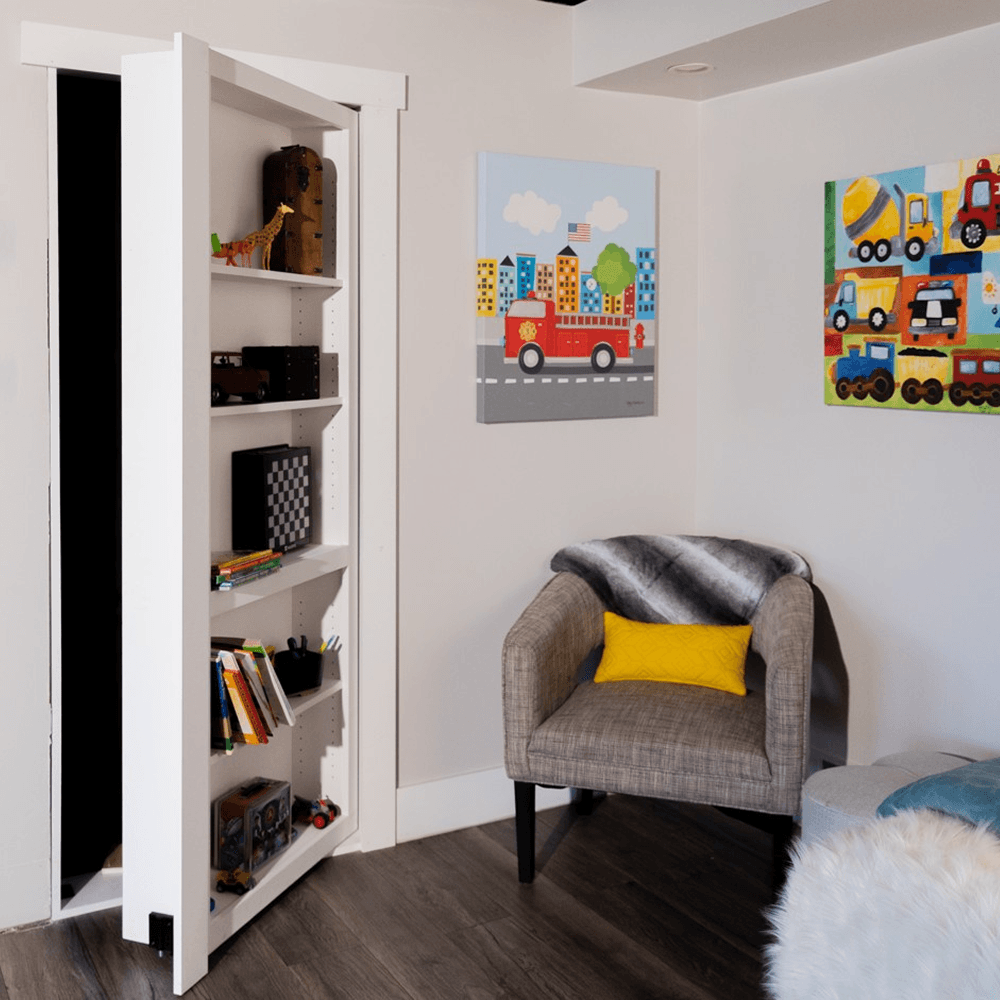 Murphy Door® Contractor Grade Bookcase Hidden Door, a white DIY bookcase door, partially open, concealing a dark room, in a modern kid's space.