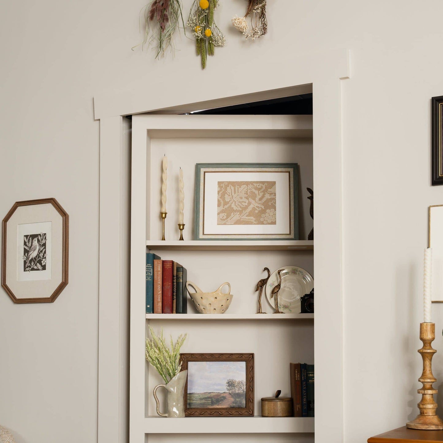 Murphy Door® DIY Quick Kit - Primed Only bookcase door, flush-mounted and filled with books and decor, seamlessly blends into a wall.