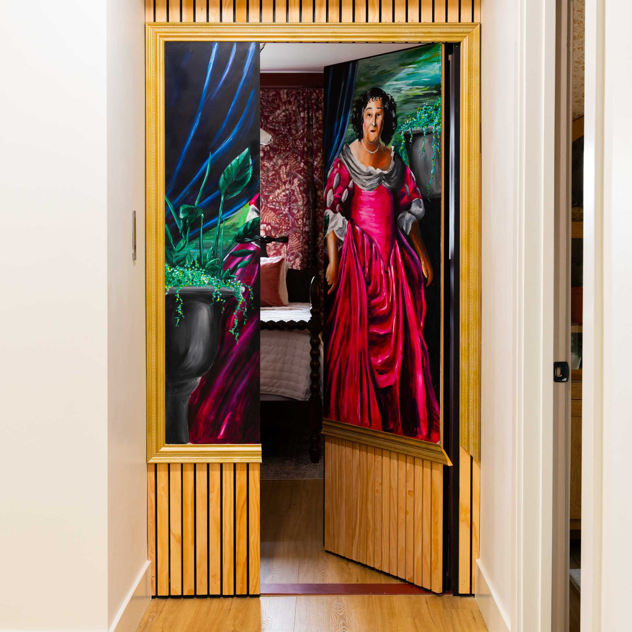 Murphy Door® hidden door disguised as portrait, featuring vibrant painting of figure in red gown, opening to reveal bedroom beyond.