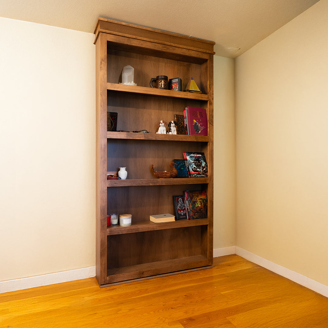 Wooden Murphy Door® bookshelf in rich brown finish with decorative items, set against cream walls and hardwood flooring.