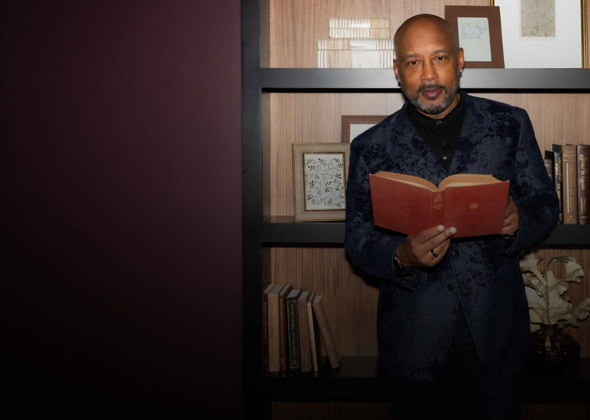 Daymond John standing beside an open Murphy Door hidden bookcase door