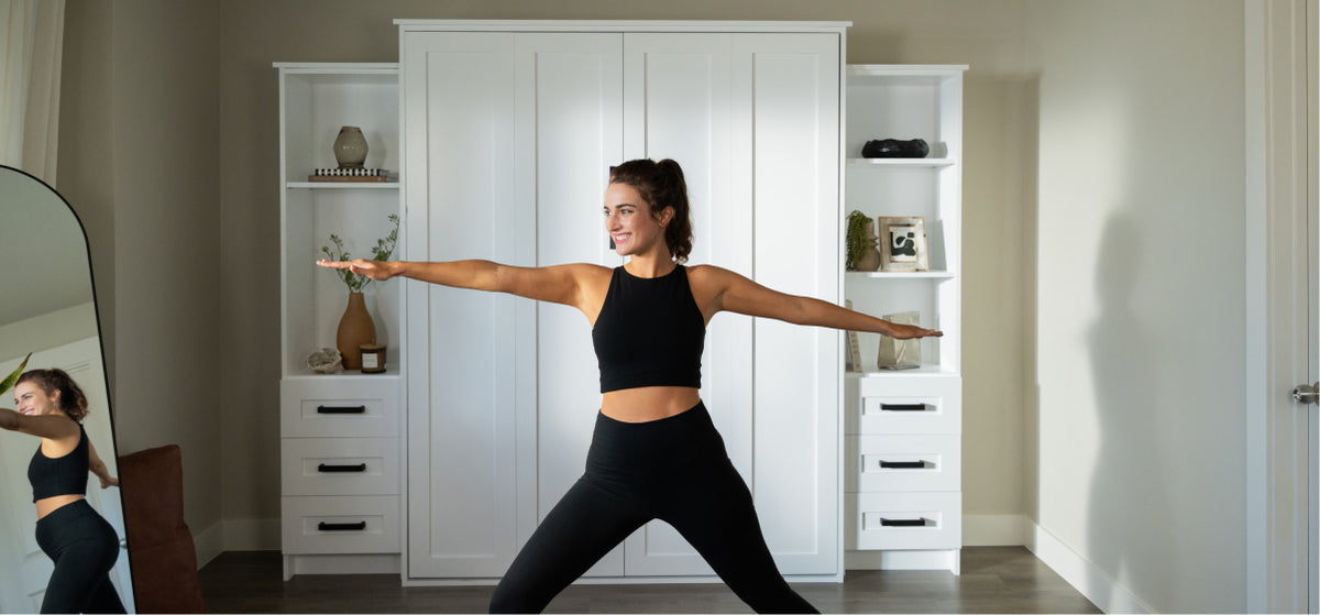 Person practicing yoga in black athletic wear against a Murphy Door® white built-in storage cabinet with decorative shelving.