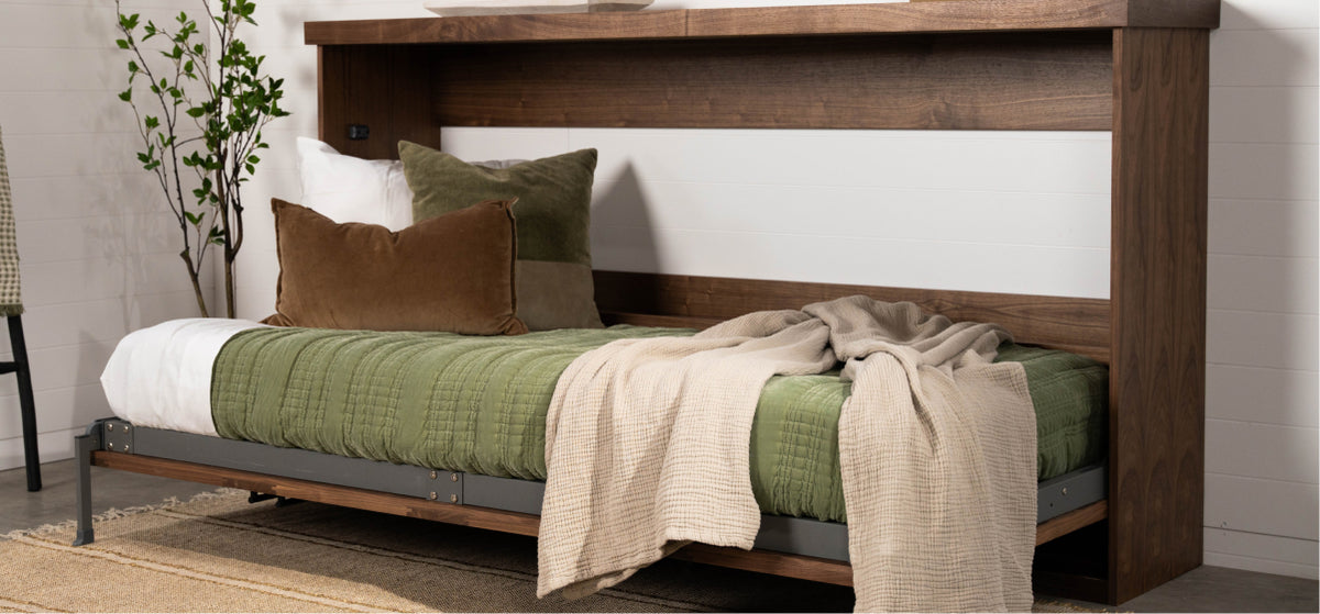 Murphy Door® wooden Murphy bed with rich walnut frame, green bedding, brown/green pillows, and beige throw on industrial-style base.