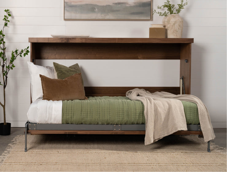 Murphy Door® wall bed frame with wooden headboard, green bedding, decorative pillows and neutral throw blanket on jute rug.