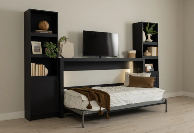 Murphy Door® wall bed with black shelving units, TV mount, and pull-down mattress with brown throw blanket on light flooring.