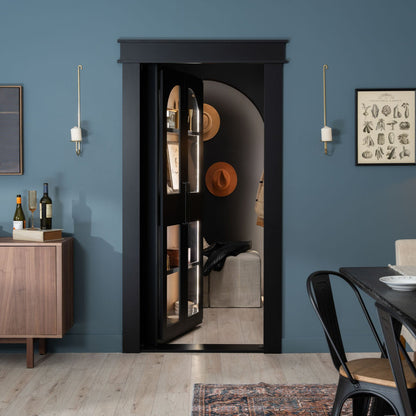 Murphy Door® black glass panel hidden door with blue walls, wooden floor, and minimalist décor revealing room with hat display.