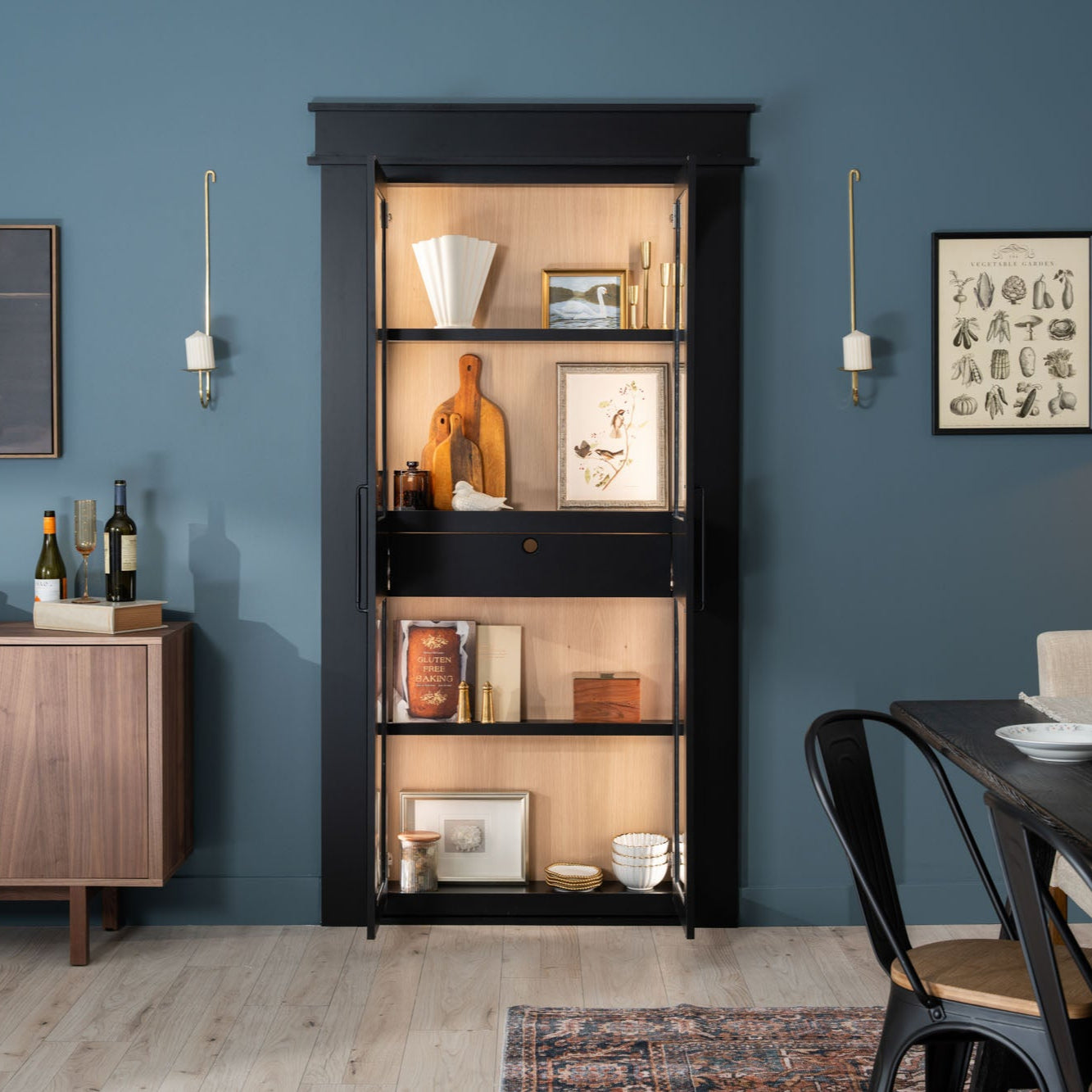Murphy Door® black bookcase hidden door with wooden interior shelving displaying decor against blue walls in modern dining area.
