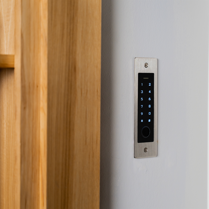Murphy Door® digital security keypad with illuminated numbers mounted on a sleek brushed metal plate beside natural wood trim.