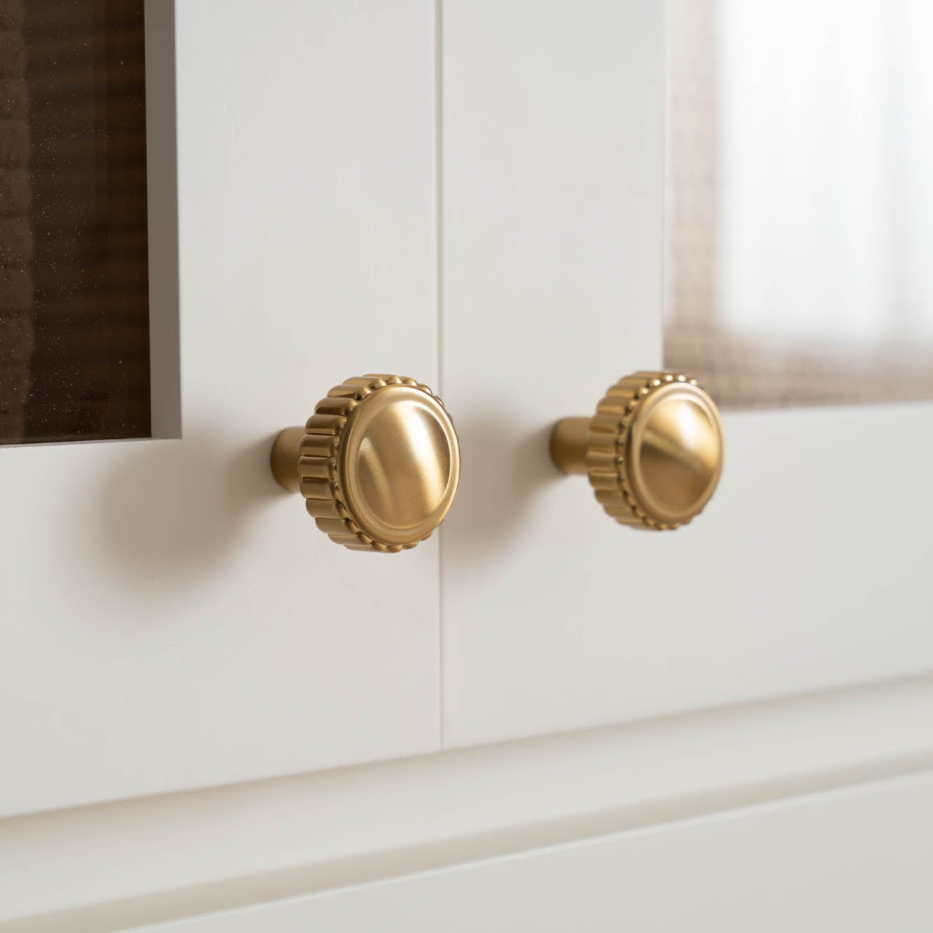 Gold decorative cabinet knobs from Murphy Door® featuring fluted edges on elegant white cabinets.