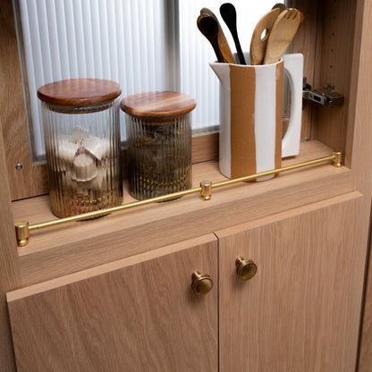 Murphy Door® kitchen cabinet with wooden glass storage jars, ceramic utensil holder and brass rail detail.