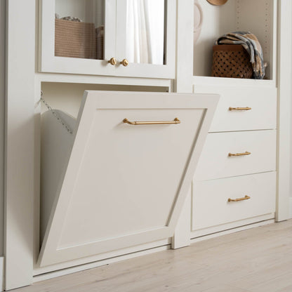 Murphy Door® white tilt-out hamper with brass handles, part of built-in cabinet system with matching hardware and storage baskets.
