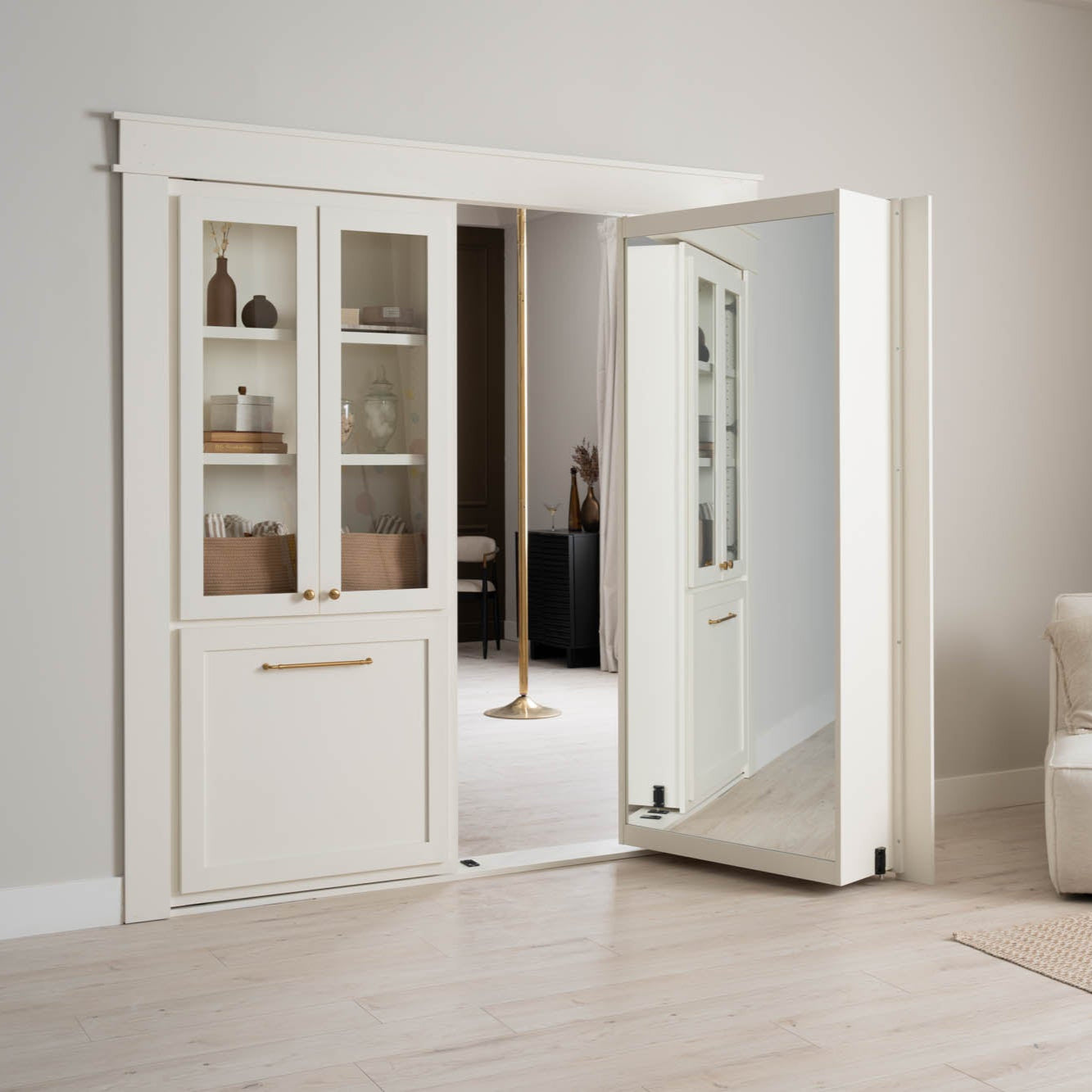 Murphy Door® white hidden door with built-in shelving, glass cabinets, and gold hardware, shown partially open in a minimalist interior.