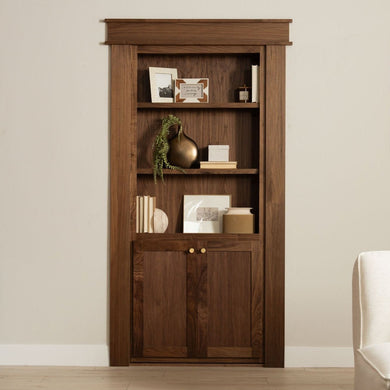 Murphy Door® wooden bookcase hidden door in rich walnut finish with decorative shelving and cabinet storage below.