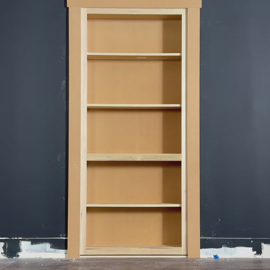 Man installs Murphy Door® Hidden Door Starter Kit (DIY bookcase door) into a dark gray wall, demonstrating its flush-mount swing.