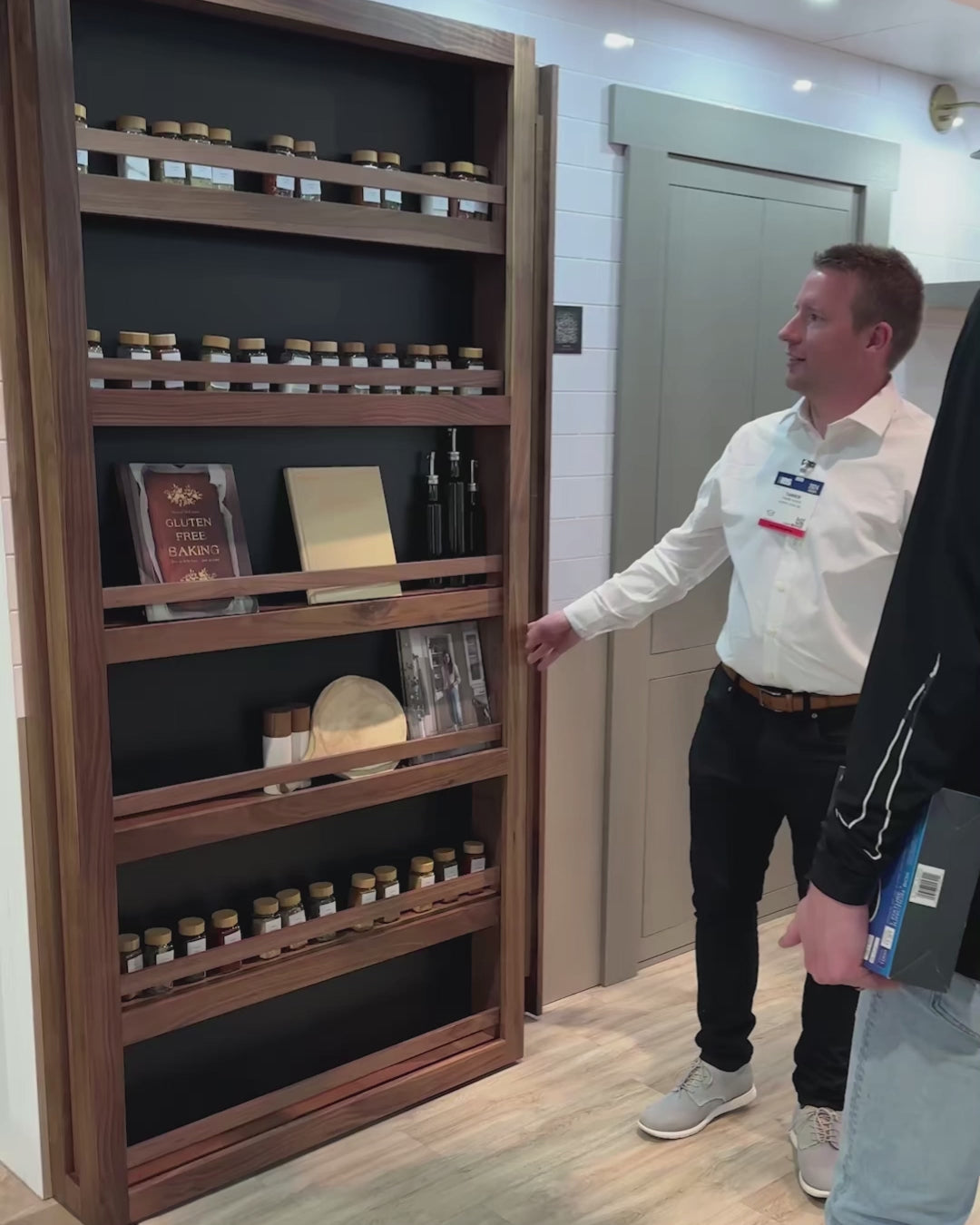 Murphy Door® Slideaway Murphy Bookcase, a flush mount bookcase door, slides open, revealing hidden pantry space with spices.