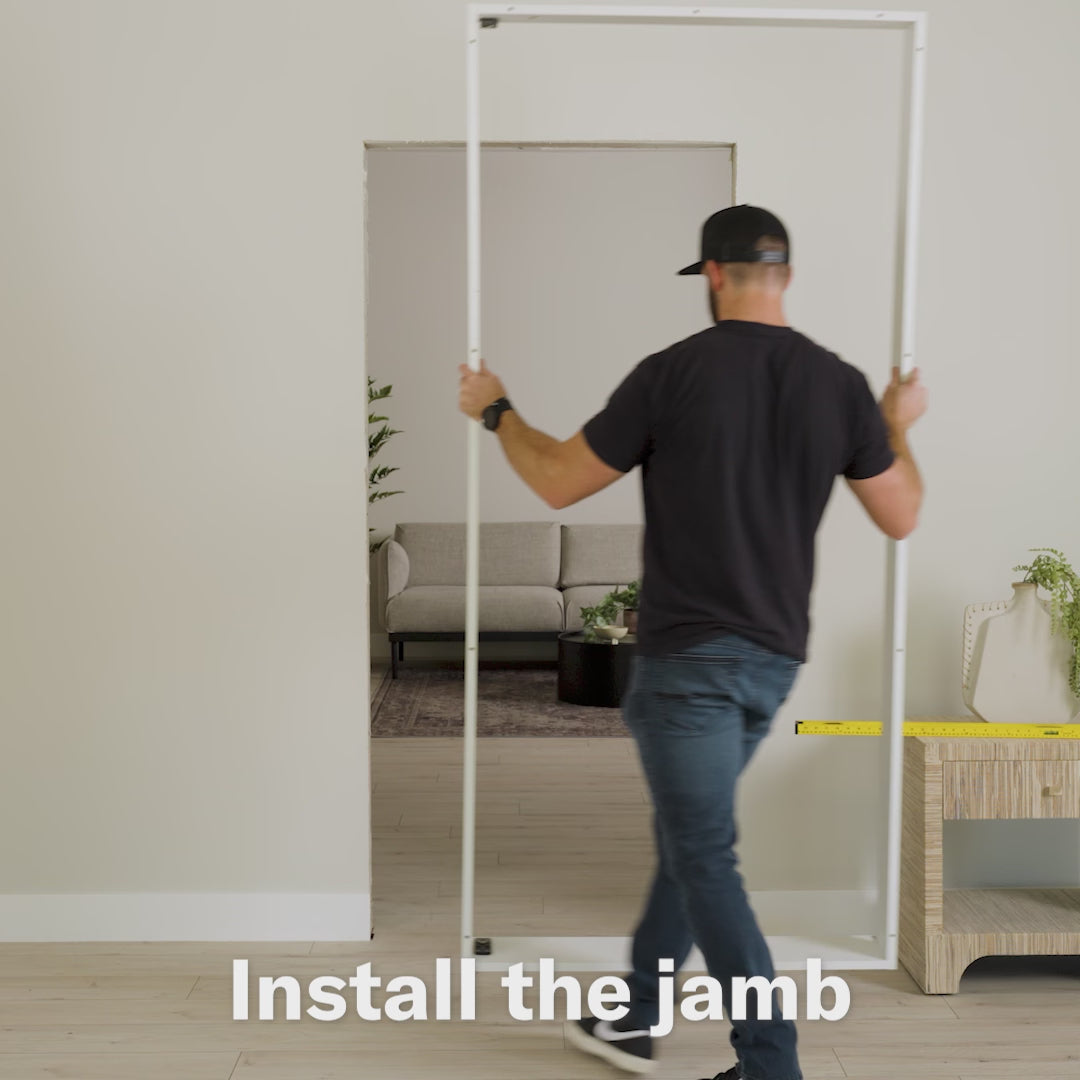 Person installing white Murphy Door® hidden door frame with both hands positioned on vertical jamb